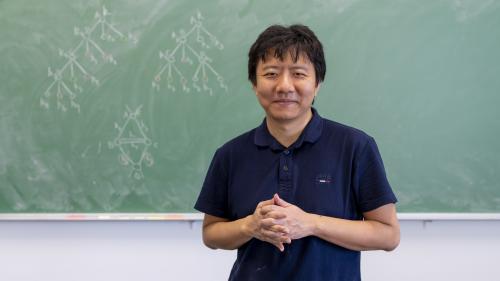 Yu Deng in front of a blackboard