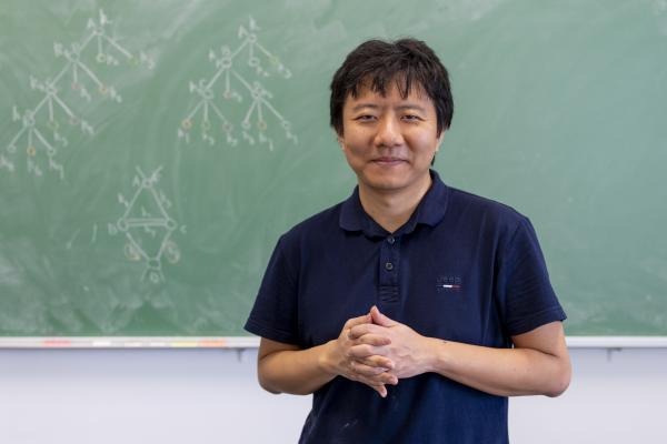 Yu Deng in front of a blackboard