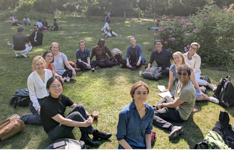 A group having a focussed discussion in the sunshine on the grass