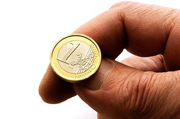 A hand shown about to flip a one euro coin