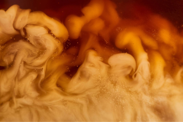 Close up of milk mixing into coffee (Image: Adobe Stock)